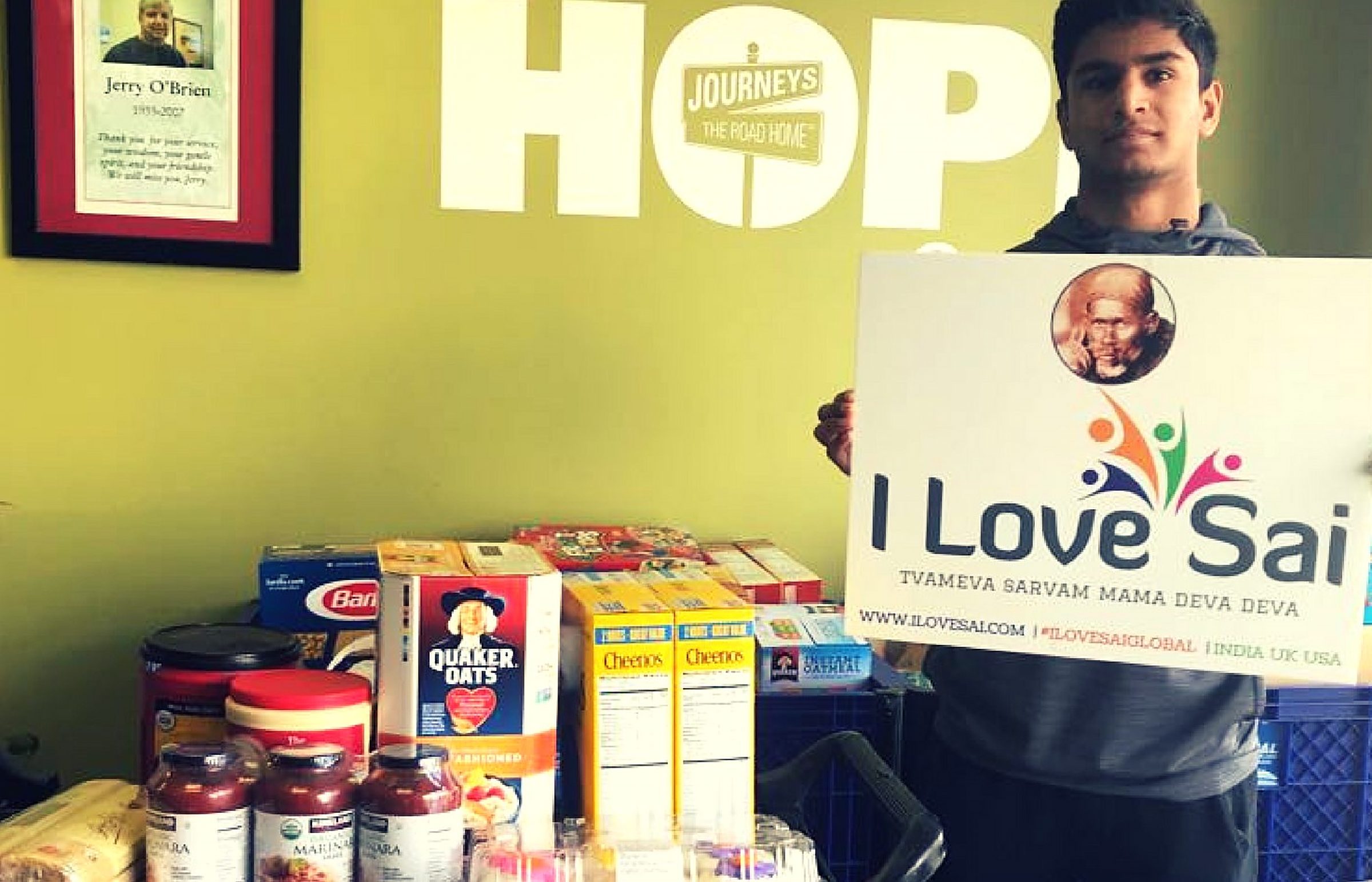 An I Love Sai volunteer beside donated groceries at the HOPE Center