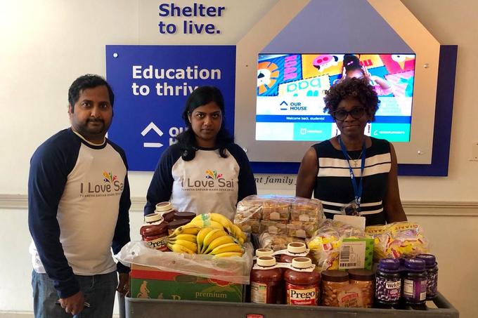 Volunteers beside a cart of donated groceries at a family shelter
