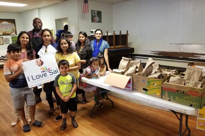 Volunteers and children beside tables of packed meals in Georgia