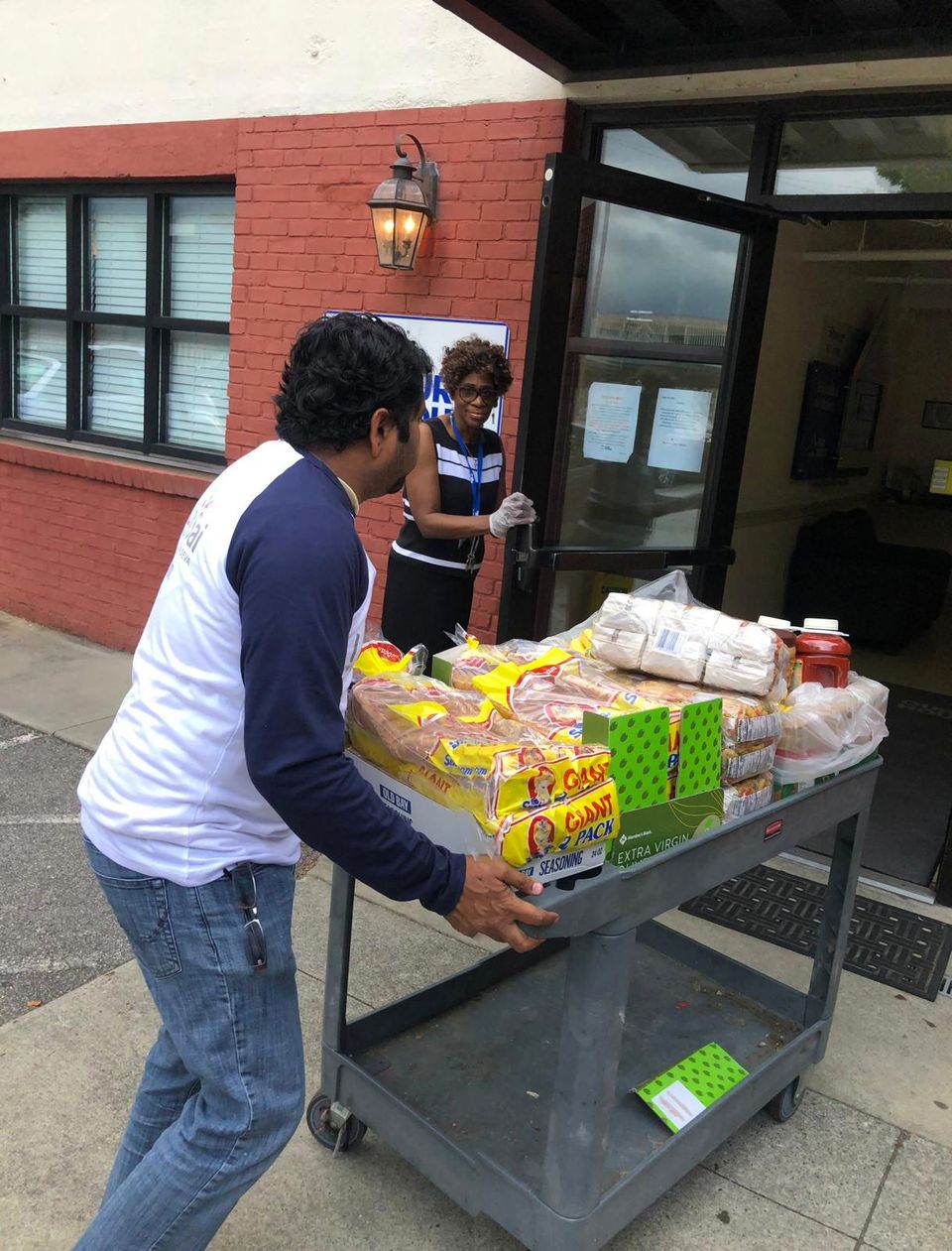 An I Love Sai volunteer wheels a cart of donated bread and groceries into a shelter